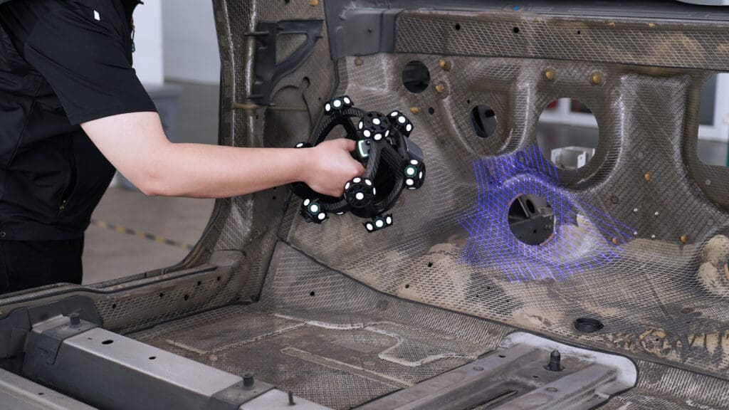 A person using the Scantech NimbleTrack 3D Wireless Scanner to scan the interior of a car's shell while on the production line